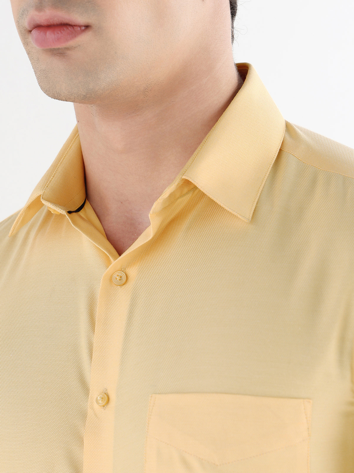 Close-up of a person wearing a yellow shirt with a collar.