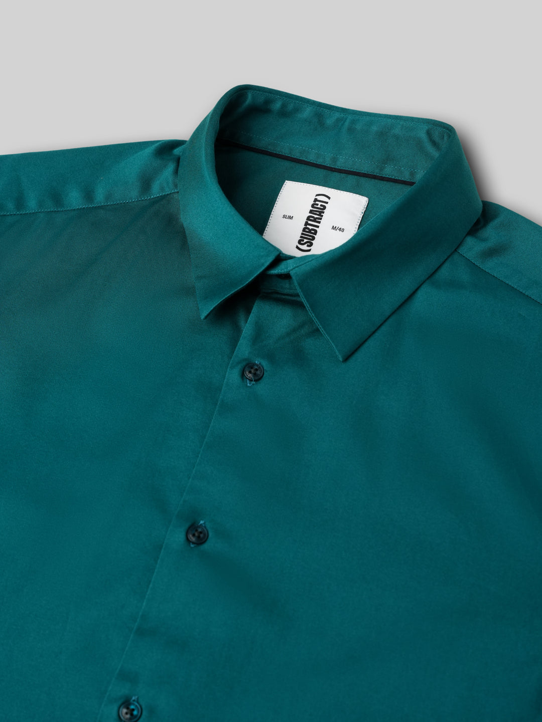 Teal shirt with a brand label on a light gray background