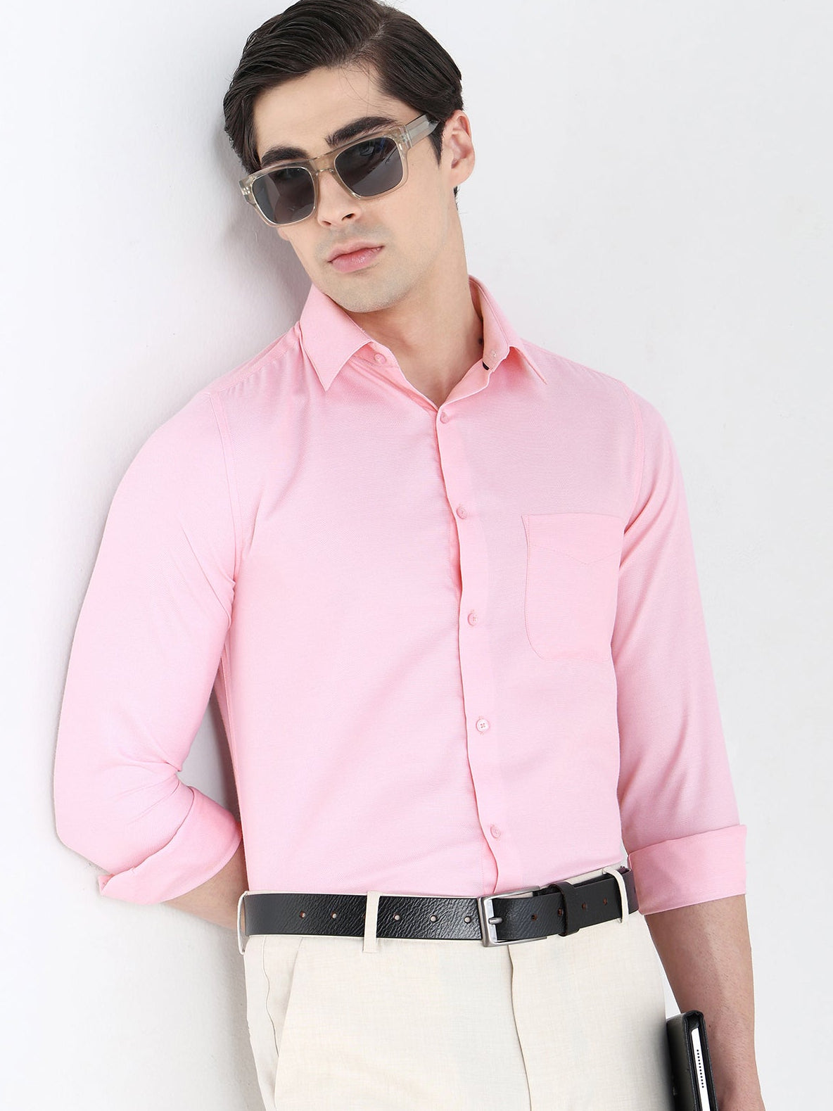 Man wearing a pink shirt and sunglasses against a white background