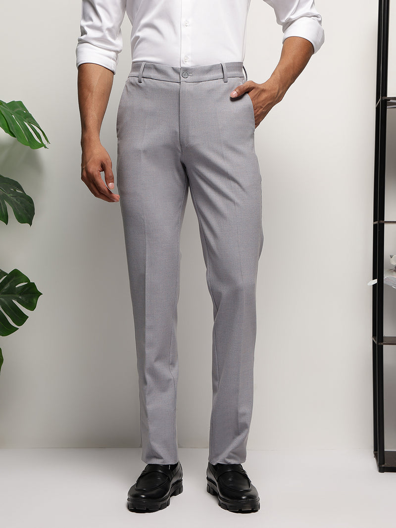 A man standing in a semi-profile pose wearing light blue striped formal trousers with a slim fit and a flexible waistband.